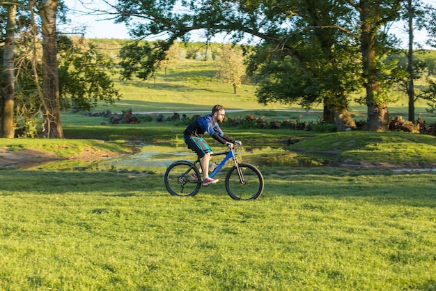 Ciclista en prados verdes en una tarde de verano hermoso paisaje