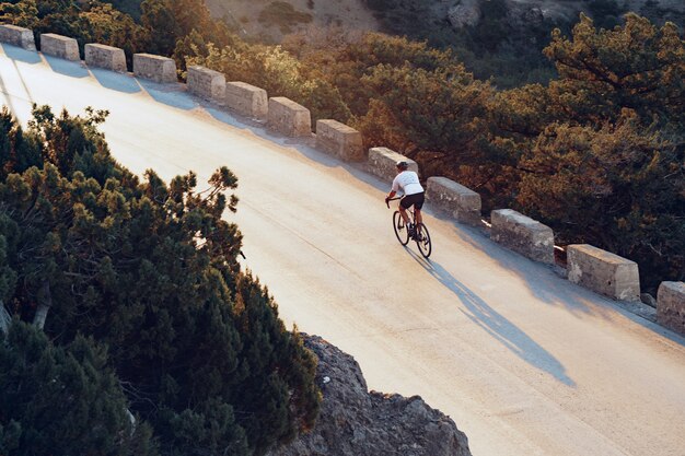 Ciclista profesional en una carretera de montaña al amanecer.