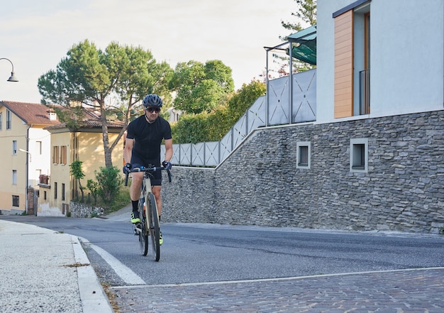 Ciclista profesional con casco protector de ropa deportiva y gafas de entrenamiento en la carretera