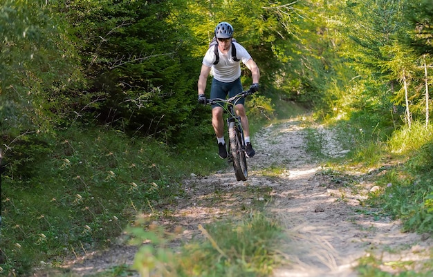 Ciclista profesional montando cuesta abajo una bicicleta de montaña lanzando un sendero forestal Deporte de aventura extremo