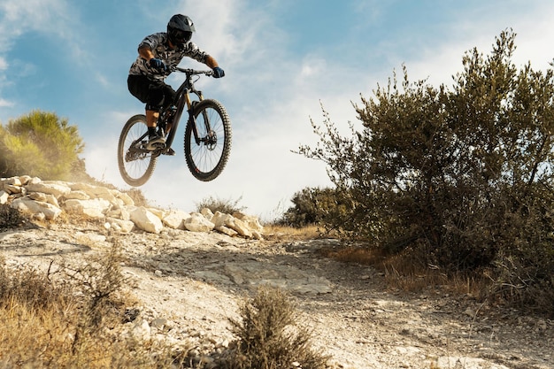 Ciclista profesional saltando durante el descenso en su bicicleta en las montañas