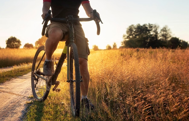 Ciclista profissional anda em uma estrada de terra em um dia ensolarado de verão Gravel bike Offroad