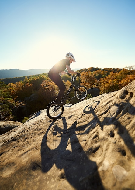 Ciclista profissional equilibrando-se em uma bicicleta experimental ao pôr do sol