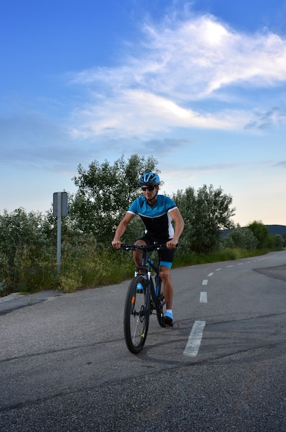 Ciclista que va en bicicleta de montaña por un camino solitario