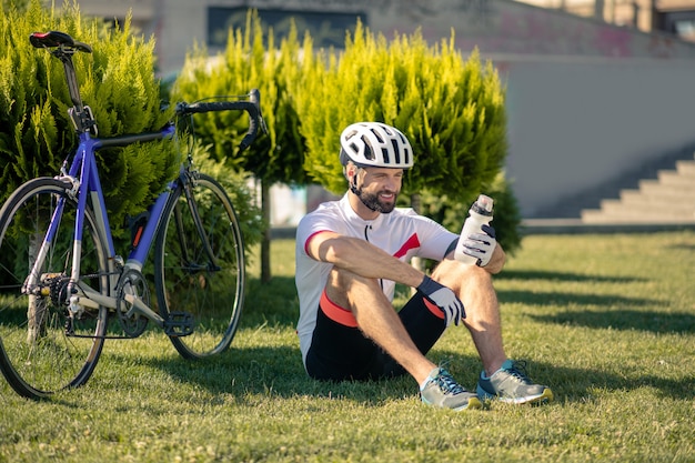 Ciclista sentado en el césped cerca de la bicicleta