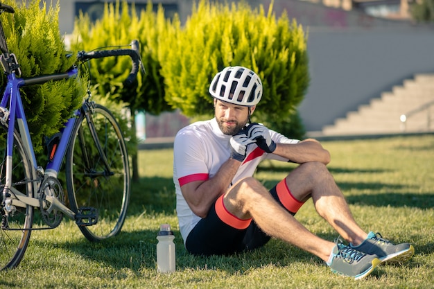 Ciclista sentado na grama perto da bicicleta