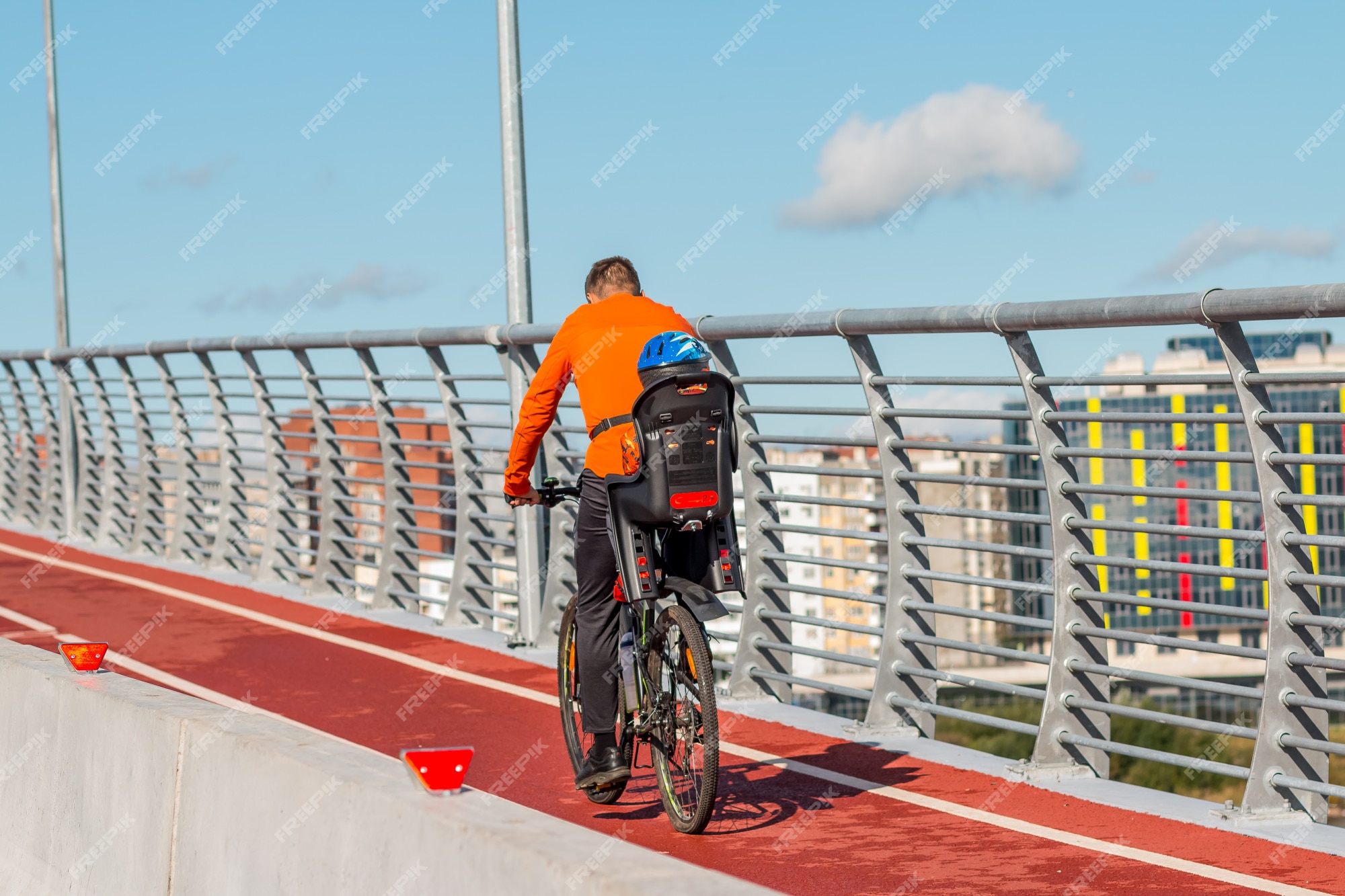 Ciclista con silla infantil y bebé. familia en ropa de abrigo en la ciudad en el puente. niño montando bicicleta. | Foto Premium