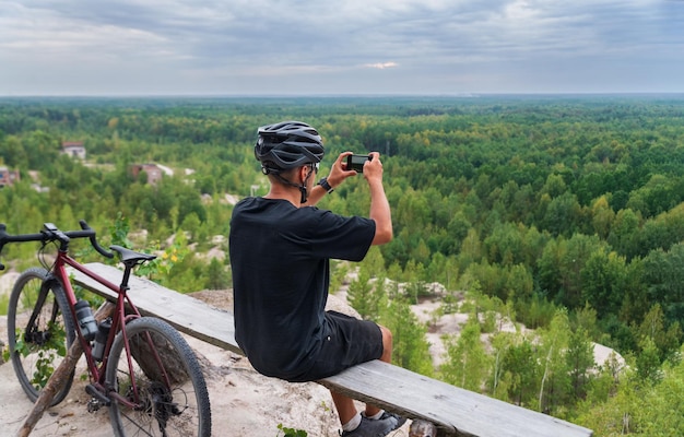 Un ciclista toma fotos de un hermoso paisaje en su teléfono móvil mientras entrena en bicicleta