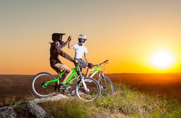 Ciclistas com bicicletas de montanha na colina à noite