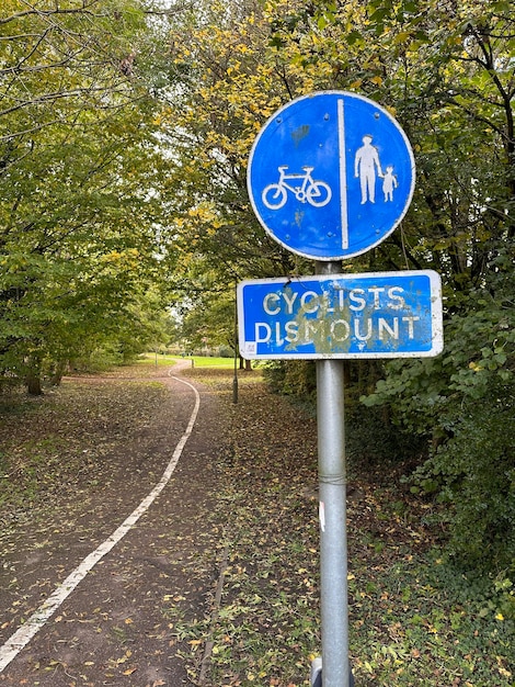 Foto ciclistas desmontam e sinal de caminho para pedestres no parque