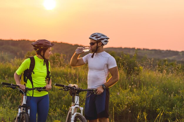 Los ciclistas, un hombre y una mujer, se detuvieron a beber agua en el viaje.