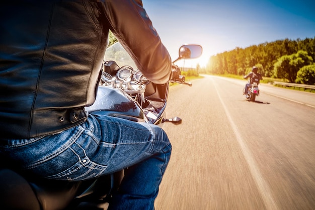 Los ciclistas que conducen una motocicleta recorren la carretera asfaltada (movimiento borroso). Vista en primera persona. Centrarse en el tablero de instrumentos de una motocicleta