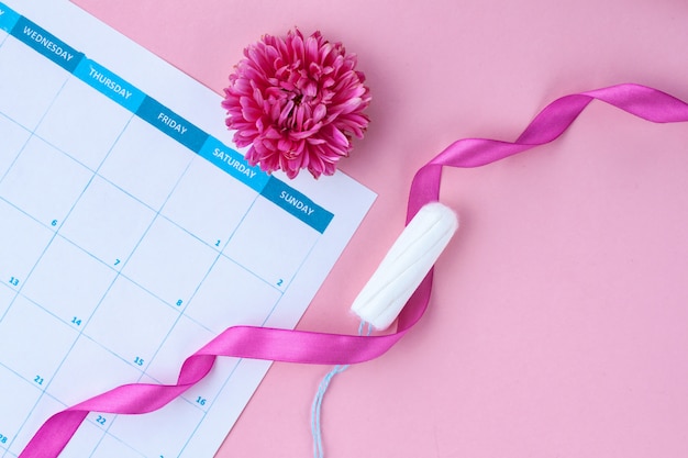 Ciclo menstrual regular. Tampones, calendario de mujer, flores. Cuidado de la higiene durante los días críticos. Atención de salud femenina y ginecológica.