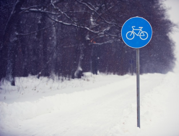 Ciclo sinal de pista coberta de neve contra uma floresta escura