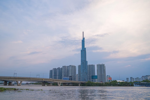 Cidade de Ho Chi Minh, Vietnã, 10 de dezembro de 2022 Vista aérea do pôr do sol no marco 81, é um arranha-céu super alto e ponte de Saigon com edifícios de desenvolvimento ao longo da paisagem urbana do rio Saigon à noite