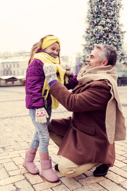 Cidade de inverno. Homem bonito com um sorriso no rosto enquanto fala com a filha