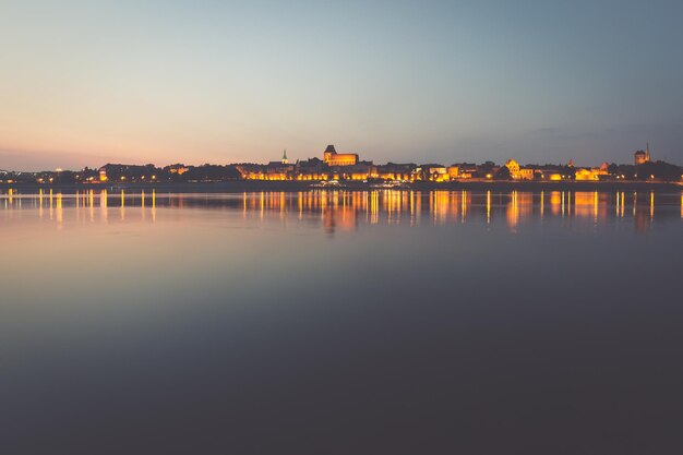 Foto cidade de torun, na polônia, horizonte da cidade velha à noite a partir do rio vistula