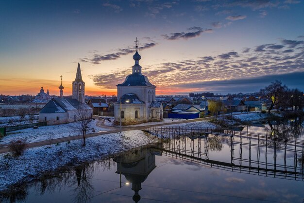 Cidade russa Suzdal ao pôr do sol Igreja da Epifania e a ponte sobre o rio Kamenka