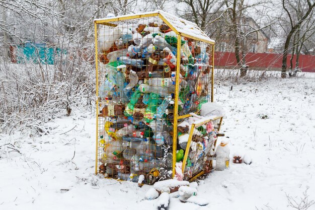 Cidade ucraniana de Romny, 26 de dezembro de 2022 Garrafas de plástico em uma lata de lixo conceito de gerenciamento de resíduos Um recipiente para garrafas de plástico em uma rua com neve de inverno Conceito de reciclagem de resíduos