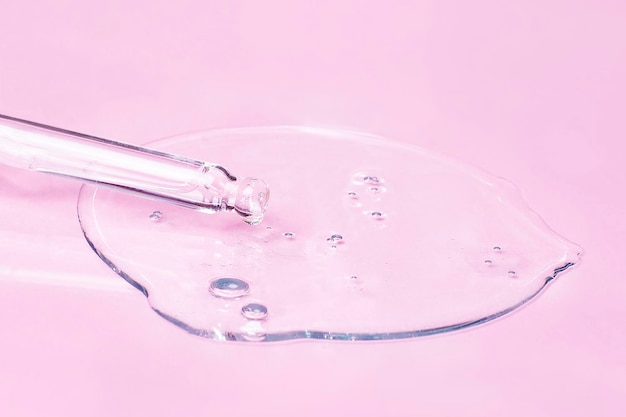 Ácido de óleo cosmético ou soro e pipeta em um fundo rosa