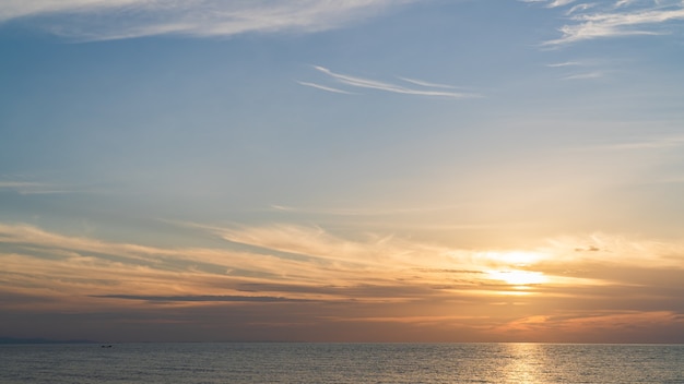 Cielo del atardecer sobre el mar por la noche con luz solar naranja