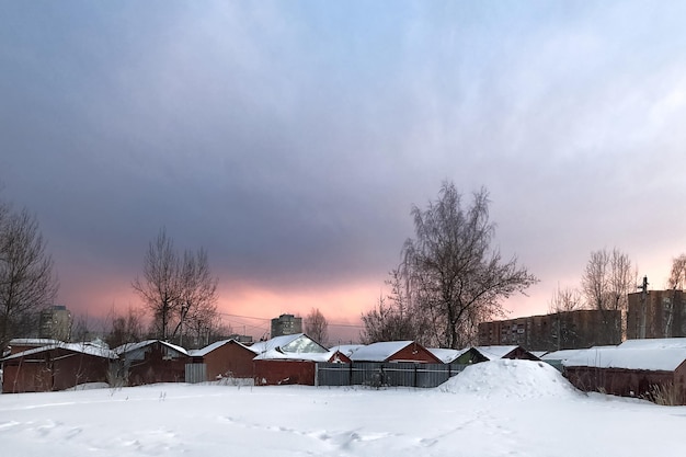 Cielo del atardecer sobre los tejados nevados de las casas de pueblo