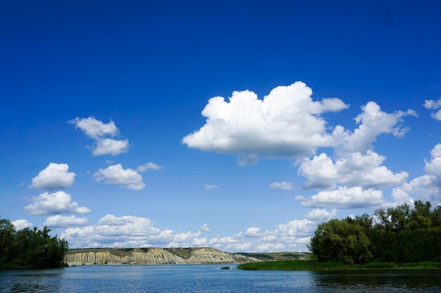 Cielo azul brillante con nubes blancas río árboles y montañas