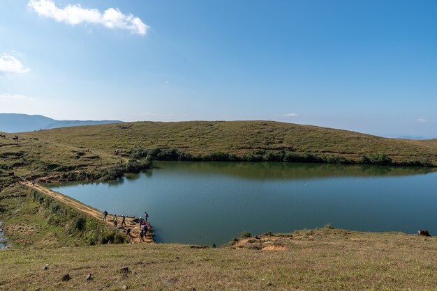 Bajo el cielo azul, el lago natural de la pradera tiene hierba amarilla y agua azul.