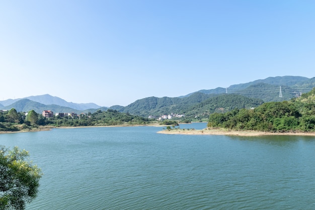 Cielo azul, montañas verdes y árboles rodean el lago.