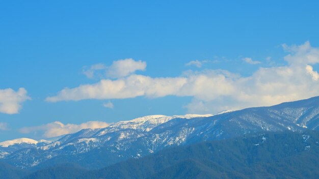 Cielo azul y nubes blancas esponjosas paisaje montañoso cadena montañosa azul en time-lapse de nieve