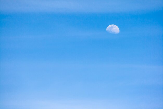 Cielo azul con nubes difusas horizontales y la luna en su creciente fase lunar gibosa