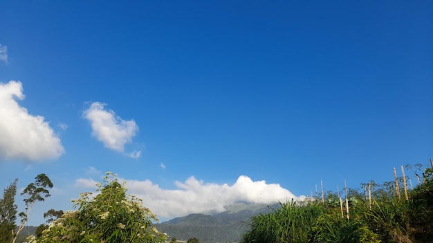 Un cielo azul con nubes y montañas al fondo