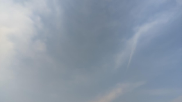 Un cielo azul con nubes y un rastro blanco en el medio.