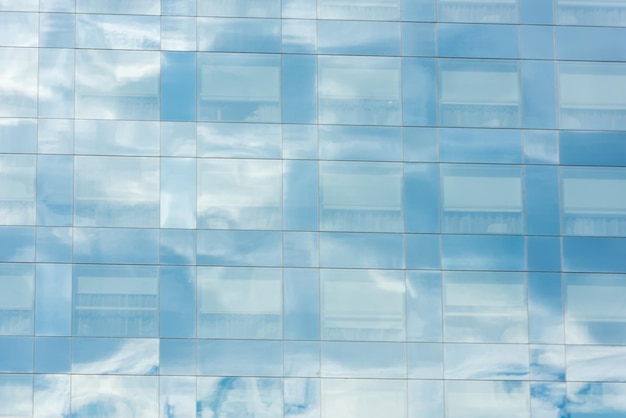 Cielo azul y nubes reflejadas en las ventanas del edificio de oficinas moderno