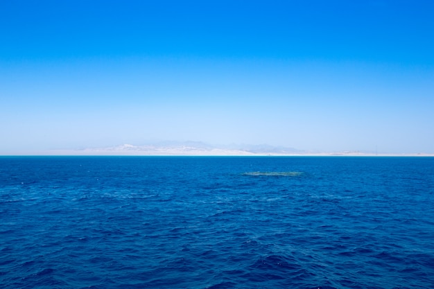 cielo azul sobre mar en calma con reflejo de sol