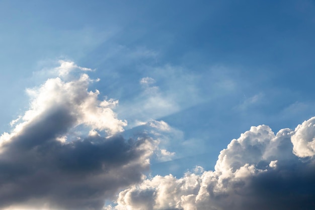 El cielo azul tiene nubes oscuras en la parte inferior de la imagen y la luz del sol brilla desde la esquina inferior izquierda de la imagen