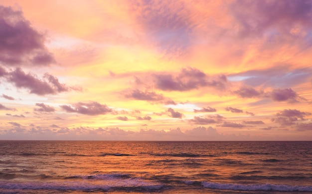 Cielo colorido como fondo. Ola suave del mar en la playa de arena