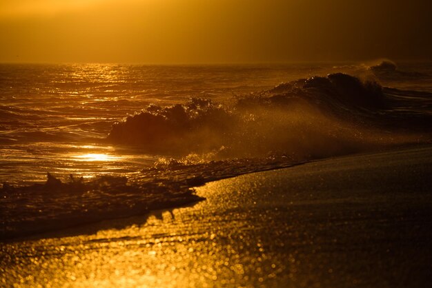 Cielo dorado y agua del océano Salpicaduras de olas Puesta de sol sobre el mar con panorama de cielo dramático dorado Mar en calma con cielo al atardecer Fondo de océano y cielo