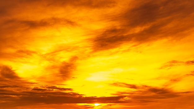 Cielo dorado con sol y nubes.