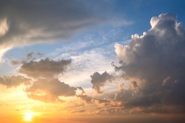 Cielo dramático al atardecer con nubes hinchadas iluminadas por el sol poniente de color naranja.