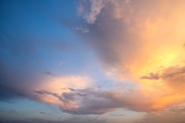 Cielo dramático al atardecer con nubes hinchadas iluminadas por el sol poniente de color naranja.