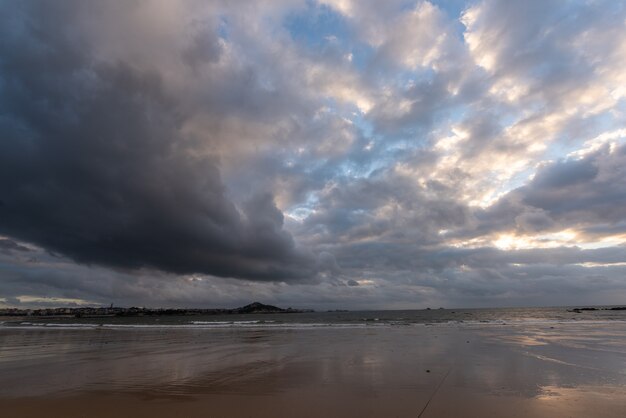 El cielo está cubierto de nubes oscuras y la playa está nublada.