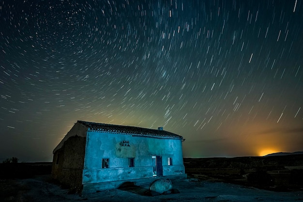 Cielo estrellado sobre una casa rural abandonada.