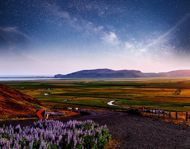 Foto cielo estrellado sobre las montañas. la carretera de asfalto con marcas blancas. islandia