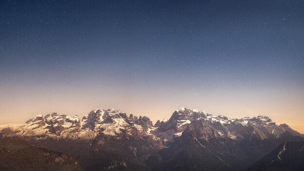 Un cielo estrellado sobre montañas con la luna arriba