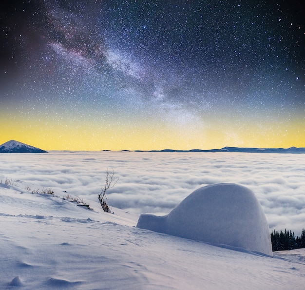 Cielo estrellado y la Vía Láctea una yurta en las montañas de niebla de invierno