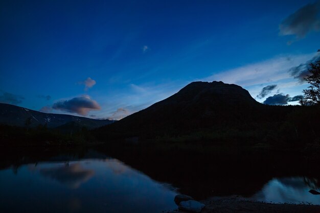 El cielo con las estrellas al amanecer, reflejado en el agua de un lago de montaña.