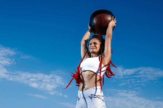 Cielo de fondo Mujer atlética con balón médico Fuerza y motivaciónFoto de mujer deportiva en ropa deportiva de moda