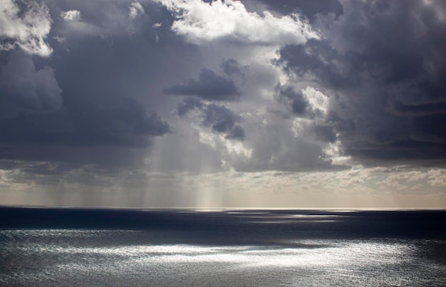 Un cielo gris con nubes La luz del sol se asoma a través de las nubes y cae sobre el mar Textura de fondo