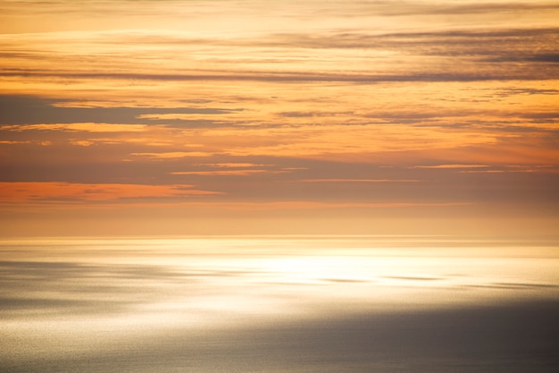 El cielo y el mar se mezclan en un color naranja al atardecer.